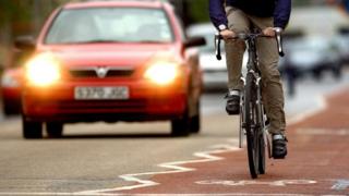man cycling in front of car