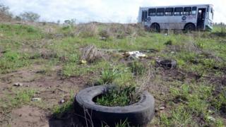Общий вид показывает автобус (сзади) на поле, поскольку сотрудники Генеральной прокуратуры штата Веракрус (незаметно) не разрешили доступ к Колинас-де-Санта-Фе в Веракрус, Мексика, 14 марта 2017 года
