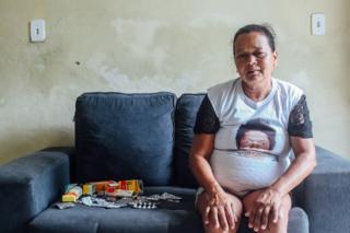 Josilene Batista sentada no sofá da casa do filho