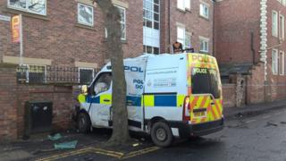 The damaged police van and the smashed wall