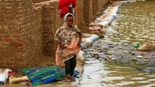 فتاة سودانية تسير وسط مياه الفيضانات.