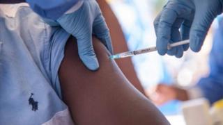 A health worker injects a patient