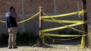 A forensic expert takes a photo at the site where a mass grave was discovered at El Mirador neighbourhood in Tlajomulco de Zuniga