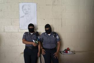 Weibliche Gefängniswärter, die zum Schutz ihrer Identität Sturmhauben tragen, stehen vor einem Porträt von Nelson Mandela im Strafzentrum von Quezaltepeque, El Salvador. 9. November 2018.