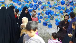 Orang berjalan di depan keramik biru yang dipercaya bisa mengusir mata setan, atau oleh warga setempat disebut sebagai ibu dari tujuh mata, di Najaf, Irak, 10 Februari 2015.