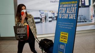 Woman wearing a face mask arrives at Heathrow airport