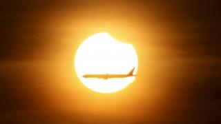 シンガポール上空で部分日食の前を通過する飛行機(9日)