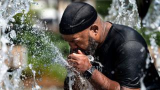 A man cools off in a fountain at Inner Harbor in Baltimore, Maryland, on 30 June 2021