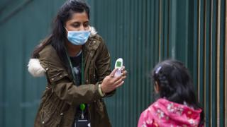 A child has their temperature checked outside a school