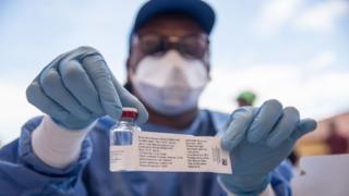 Une infirmière travaillant avec l'Organisation Mondiale de la Santé (OMS) montre un flacon contenant le vaccin Ebola lors du lancement de la campagne de vaccination Ebola.