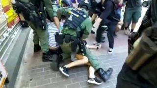 The 12-year-old girl and her brother being held down by riot police