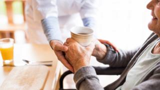 Nurse giving drink to elderly patient