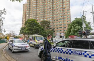 Police cars and officers outside one of the locked-down towers in Melbourne