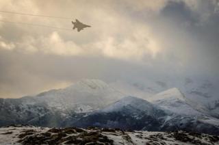 A plane flying across hills