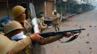 A police personnel aims his gun towards protesters during demonstrations against India's new citizenship law in Kanpur on December 21, 2019.