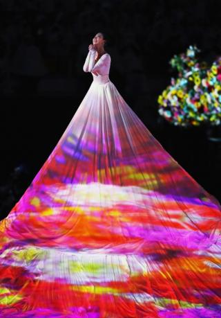 A dancer in a long white dress performs at the closing ceremony