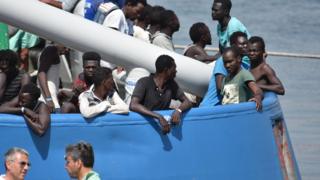 Некоторые из 650 мигрантов, которые были спасены шведским кораблем Frontex в Средиземном море у ливийского побережья, ожидают высадки в Катании, Италия, 1 июля 2017 года