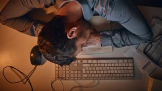 Homem dormindo em cima do computador