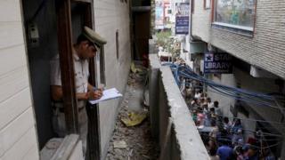 A policeman writes notes in the house where the bodies of eleven members of a family were found dead in Burari, in New Delhi, India, July 1, 2018