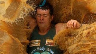 Un empleado cayendo en un enorme charco de agua enlodada