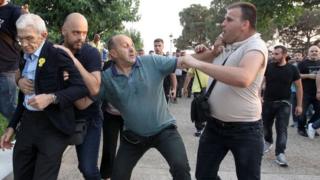 Mayor of Thessaloniki, Yiannis Boutaris (L), is protected from an attack by a group of nationalists during Remembrance Day on 19 May 2018.