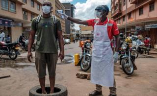 A Red Cross volunteer measures the temperature of a man at Nakasero market in Kampala, Uganda - Wednesday 1 April 2020