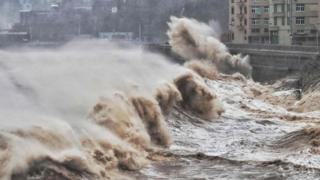 Waves hit a sea wall in front of buildings in Taizhou, China's eastern Zhejiang province on August 9, 2019.