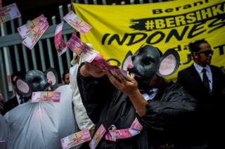 Seorang pengunjuk rasa mengenakan topeng tikus perlambang koruptor