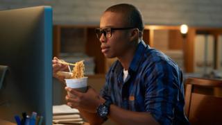 A man eating in front of a computer