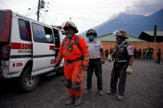 Firefighters are seen partially covered with ash