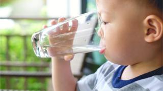 A boy drinks water in a glass