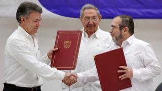El presidente de Cuba, Raúl Castro, observa a su homólogo de Colombia, Juan Manuel Santos (izq.) darse la mano con el líder de las FARC Rodrigo Londoño, alias Timochenko, tras firmar un acuerdo de cese el fuego en La Habana, Cuba.