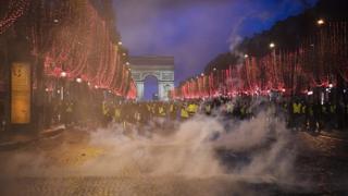 "Yellow vests" (gilets jaunes) demonstrators stand amid tear gas on the Champs Elysees avenue in front of the Arc de Triomphe in Paris on December 8, 2018