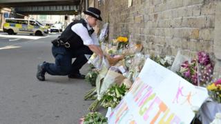 Londra'da bir polis Finsbury Park'ta hayatını kaybeden kişi anısına duvara çiçekler bırakıyor