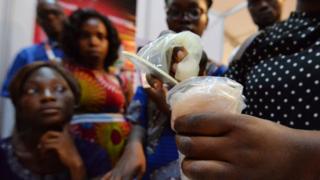 A woman shows how to use female condoms at a stand on December 8, 2017 in Abidjan, as part of the 19th ICASA conference (International Conference on AIDS and STIs in Africa).