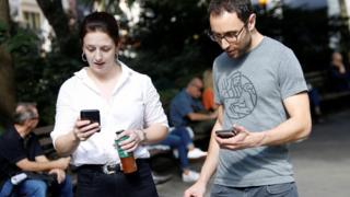 People look at their text alert at Madison Square Park in Manhattan, New York