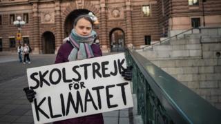 Greta holds her protest sign outside Swedish parliament
