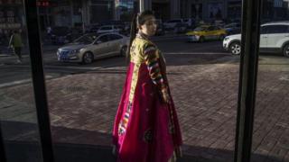 Una norcoreana trata de captar la atención de los viandantes en la ciudad china de Dandong, para que entren a su restaurante.