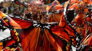 Women dressed as butterflies dance during the parade
