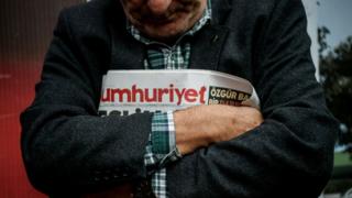 Kollarının arasında Cumhuriyet gazetesi tutan bir adam.