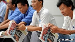 Readers scan the papers in Singapore