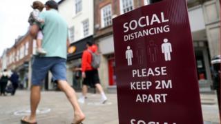 A man walking past a social distancing sign