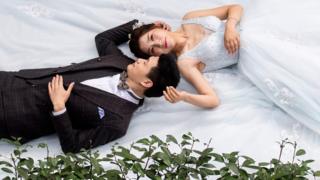 Bride and groom lying in a park
