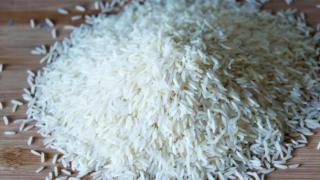 Small pile of long grain white rice over a wooden surface