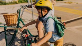 Boy cycling to school with parent
