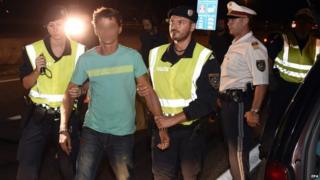 Austrian Police officers detain the driver of a car carrying nine adults and two childrenon patrol on the motorway near the Austro-Hungarian border, in Nickelsdorf, Austria (30 August 2015)