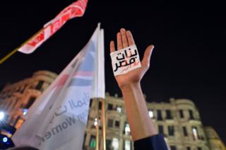 يد ولافتة مكتوب عليها "النساء خط أحمر"