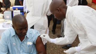 A health worker, right, cleans a man's arm before injecting him with a Ebola vaccine in Conakry, Guinea.