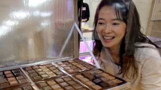 A woman looks at a tray of chocolates
