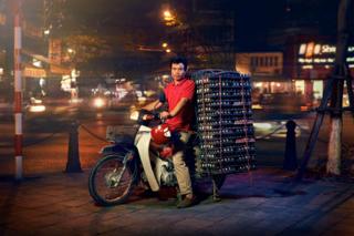 A man posed on a motorcycle with a huge pile of eggs on the back